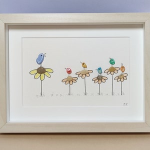 Op de afbeelding: Een ingelijst kunstwerk met een blauwe vogel die zingt op een gele bloem, met vijf andere kleurrijke vogels die op gele bloemen zitten. Het kunstwerk is gemaakt van kiezelsteentjes en is gesigneerd met "J.K."