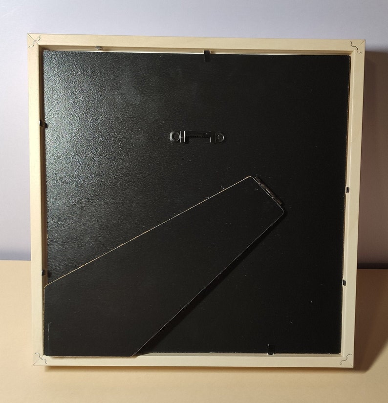 May include: A white picture frame with a black mat and a black easel stand on the back. The frame is made of wood and has a simple design.