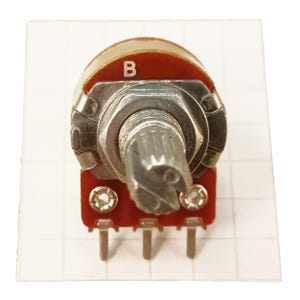 May include: A potentiometer with a red base and a silver metal body. The top of the potentiometer has the letter "B" printed on it. The control shaft is ridged and the base has three pins.