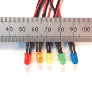 Könnte beinhalten: Fünf LED-Leuchten mit Drähten, gemessen an einem Lineal. Die Leuchten sind rot, orange, gelb, grün und blau.
