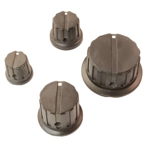 Op de afbeelding: Vier zwarte kunststofknoppen met een geribbeld ontwerp. De knoppen hebben een centraal gat en een verhoogde lijn in het midden.