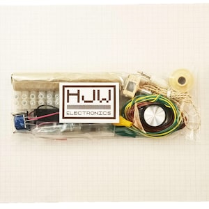 Könnte beinhalten: Ein klarer Plastikbeutel mit verschiedenen elektronischen Bauteilen. Dazu gehören Drähte, ein kleiner Lautsprecher, ein Transformator und andere Teile. Ein Etikett mit der Aufschrift "HJW ELECTRONICS" ist sichtbar.