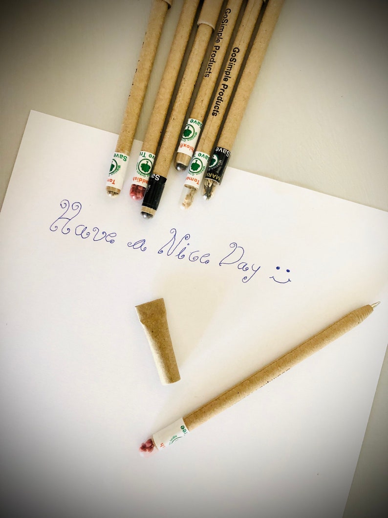 May include: A collection of eco-friendly pencils and a pen made from recycled materials, with the text "GoSimple Products" printed on them. The pencils and pen are lying on a white sheet of paper with the handwritten message "Have a Nice Day".