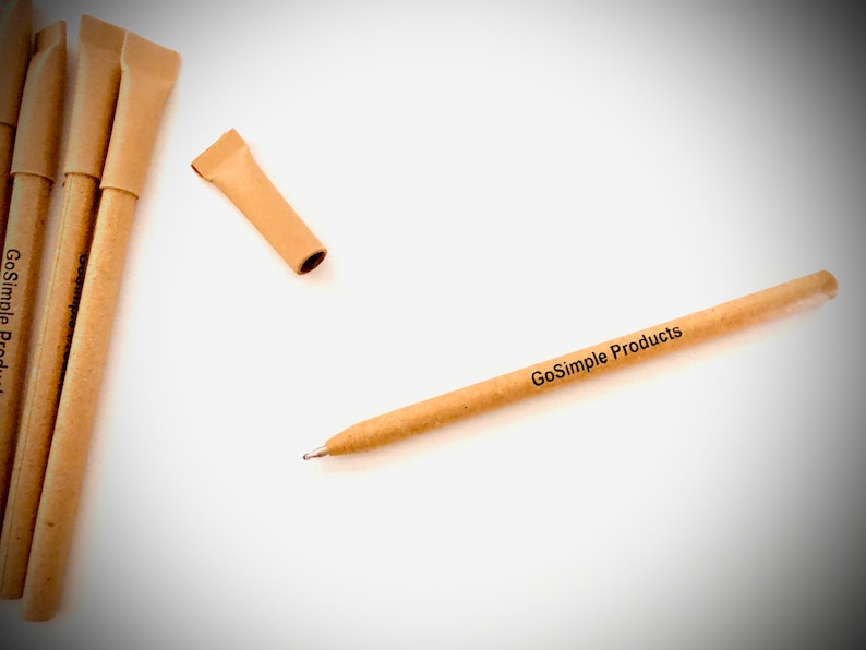 May include: A collection of eco-friendly pens made from tan-colored paper. One pen is uncapped, revealing the metal tip. The text "GoSimple Products" is printed on the pen's barrel. The pens are arranged on a white surface.