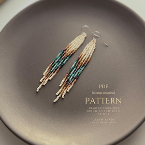 Peut inclure: Paire de boucles d'oreilles à franges perlées blanches, turquoise, marron et bordeaux. Elles sont présentées sur une assiette grise foncée. Le texte "PATTERN" est visible. Fabriqué avec des perles tchèques.