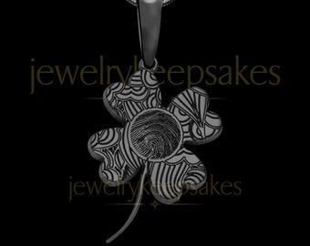 May include: A matte black four-leaf clover pendant necklace featuring an engraved fingerprint in the center and intricate line patterns on each leaf. The text jewelrykeepsakes is visible in gold lettering across the center of the image.