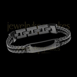 May include: Black leather bracelet with a black metal clasp and a rectangular plate with the text "jewelrykeepsakes".