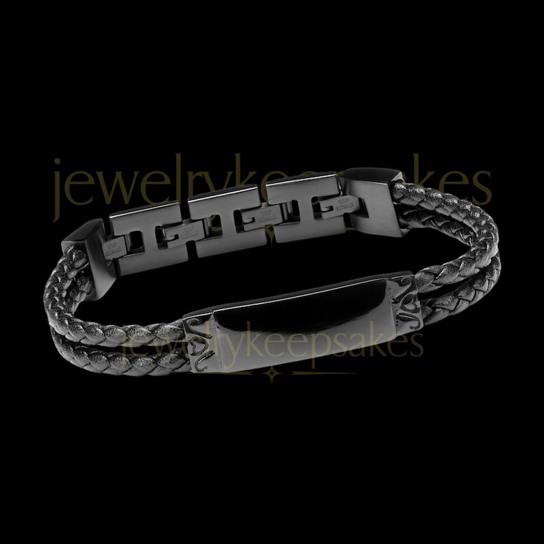 May include: Black leather bracelet with a black metal clasp and a rectangular plate with the text "jewelrykeepsakes".