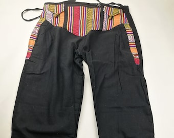 May include: Black pants with colorful patterned fabric trim around the waist and at the bottom of the legs. The fabric trim features a geometric design with red, yellow, blue, and green colors.