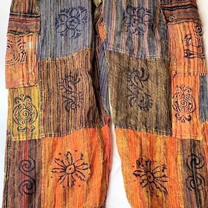 May include: Patchwork pants with a drawstring waist and side pockets. The pants are made of a variety of fabrics in shades of orange, brown, and blue, and feature a unique printed design.