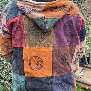 May include: A multi-coloured patchwork hooded jacket with various symbols and designs printed on each panel. The jacket is made of a soft, comfortable fabric and has a relaxed fit.