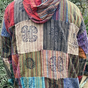 May include: A multi-coloured patchwork hooded shirt with a striped pattern and floral designs. The shirt is made of a soft, comfortable fabric and has a relaxed fit.