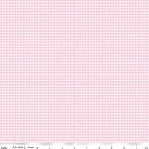 May include: A light pink fabric with a small grid pattern. The fabric has a subtle texture and a consistent color throughout. The image includes a ruler along the bottom edge, showing measurements in inches. The fabric is from Riley Blake Designs.