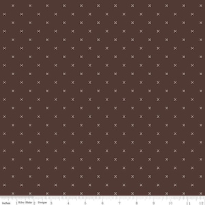 May include: A brown fabric with a white cross pattern. The fabric is a repeating pattern of white crosses on a brown background.
