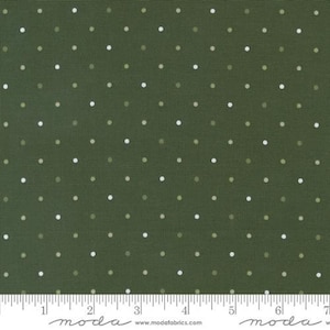 May include: Close-up of a fabric with a dark olive green background and a repeating pattern of small, evenly spaced white and light green dots. The fabric has a textured appearance. A ruler is at the bottom.