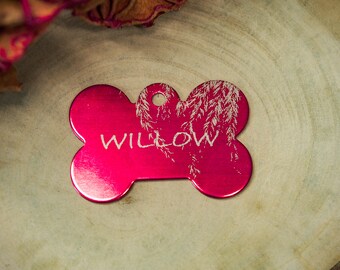 May include: A pink bone-shaped dog tag with the name "WILLOW" engraved on it. The tag has a textured design of a tree with leaves.