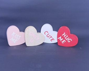 May include: Four wooden heart-shaped decorations with different colors and messages. The hearts read "Kiss Me", "Only You", "Cute", and "Hug Me".