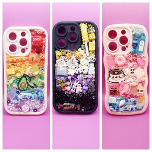 May include: Three phone cases decorated with miniature food, candy, and character charms. The left case is white with a rainbow gradient of charms. The center case is black with a monochromatic gradient. The right case is light pink with pastel charms.