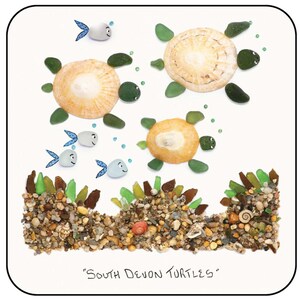 May include: An artistic depiction of sea turtles and fish made from natural materials. The turtles have shell bodies and green stone flippers. The fish are white with blue fins. The artwork is titled "South Devon Turtles".