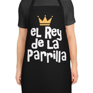 May include: Black apron with white text that reads "El Rey de La Parrilla" and a gold crown above the text.