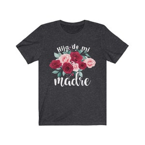May include: Dark heather grey t-shirt with a floral design and the text "Hija de mi madre" in white.