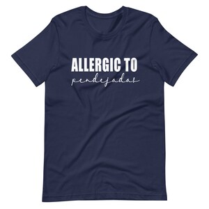 May include: A navy blue t-shirt with white text that reads "ALLERGIC TO pendejadas".