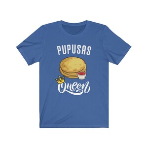 Puede incluir: Una camiseta azul real con el texto "Pupusas Queen" en letras blancas. Una imagen de dibujos animados de pupusas con un lado de salsa est&aacute; por encima del texto. Una corona dorada est&aacute; a la izquierda del texto.