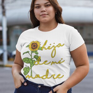 Puede incluir: Camiseta blanca con un gr&aacute;fico de girasol y el texto "hija de mi madre" en amarillo.