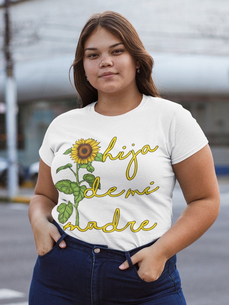 Puede incluir: Camiseta blanca con un gr&aacute;fico de girasol y el texto "hija de mi madre" en amarillo.