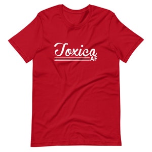 May include: Red short-sleeved t-shirt with white text that reads "Toxica AF" in a retro font.