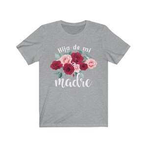 May include: Gray t-shirt with a floral design and the text "Hija de mi madre" in white.