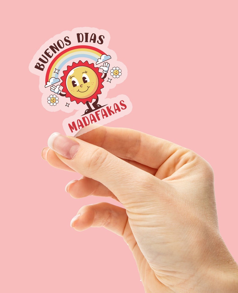 Op de afbeelding: Een sticker met een cartoonzon en regenboog, met de tekst "BUENOS DIAS MADAFAKAS" in een kleurrijk lettertype.