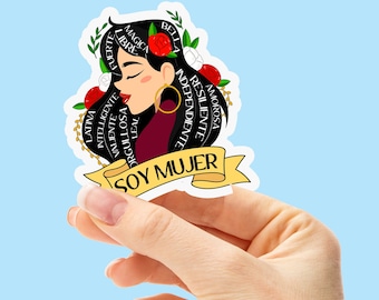 May include: A sticker featuring a cartoon illustration of a woman with black hair and a red flower. The sticker includes the words "Soy Mujer" and a list of positive adjectives in Spanish surrounding the woman's head.