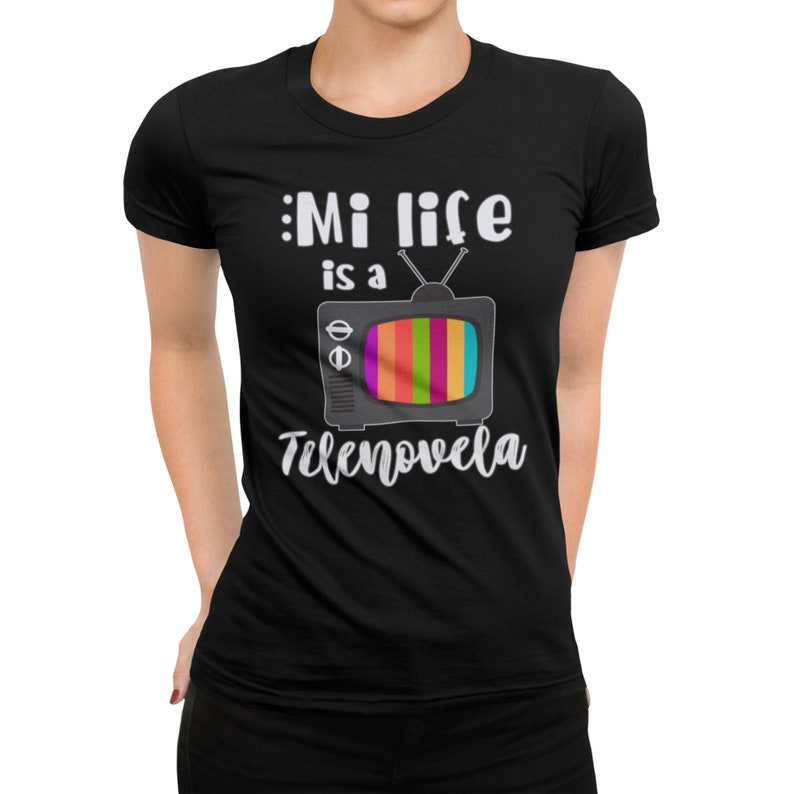 May include: Black t-shirt with white text that reads "Mi life is a telenovela" and a cartoon image of a retro television with a rainbow screen.