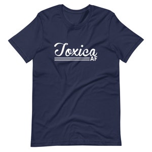 May include: A navy blue t-shirt with white text that reads "Toxica AF" in a retro font.