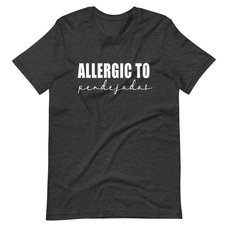 May include: Dark heather grey t-shirt with white text that reads "ALLERGIC TO pendejadas".