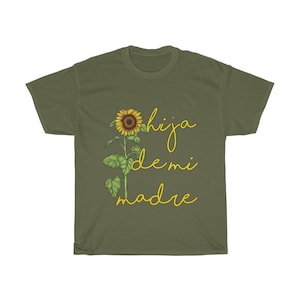 Puede incluir: Una camiseta verde con un gr&aacute;fico de girasol y el texto "hija de mi madre" en amarillo.