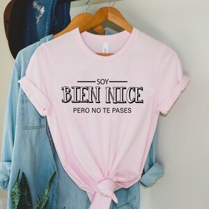 K&ouml;nnte beinhalten: Rosafarbenes T-Shirt mit schwarzem Text, der "Soy Bien Nice Pero No Te Passes" lautet.