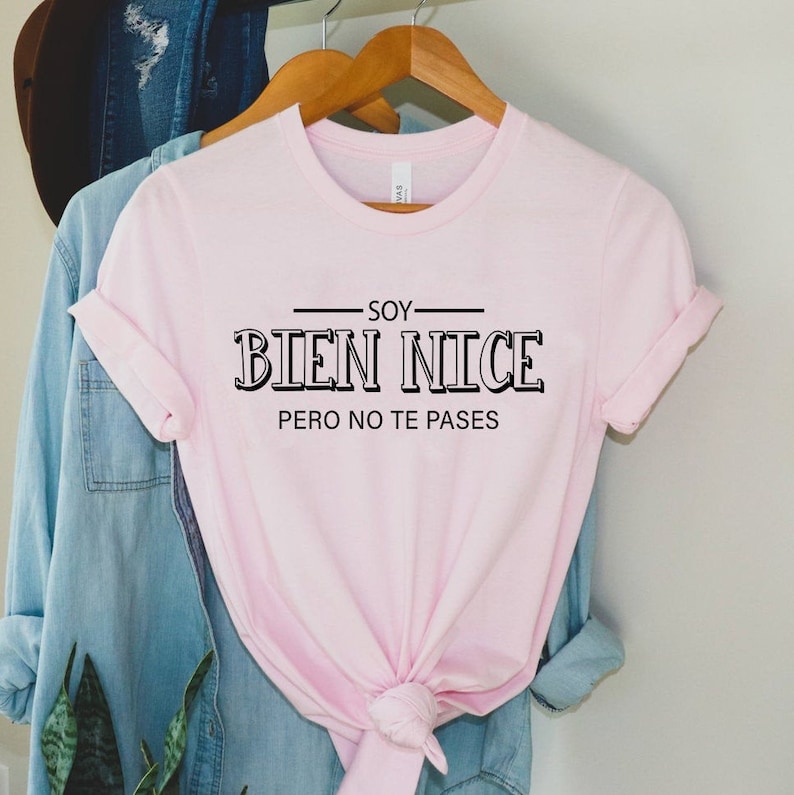 K&ouml;nnte beinhalten: Rosafarbenes T-Shirt mit schwarzem Text, der "Soy Bien Nice Pero No Te Passes" lautet.