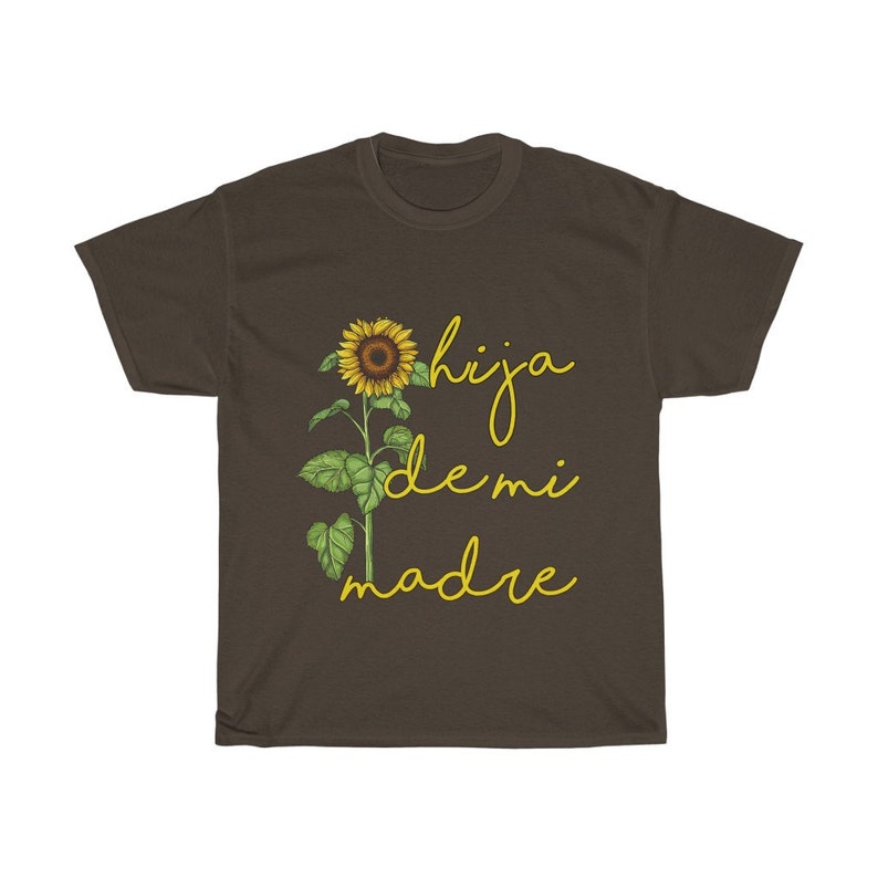 Puede incluir: Una camiseta marr&oacute;n con un gr&aacute;fico de girasol y el texto "hija de mi madre" en amarillo.