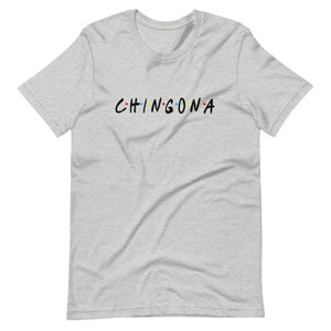 May include: A heather grey t-shirt with the text "CHINGONA" in black letters with colorful dots between the letters.