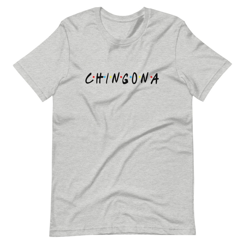 May include: A heather grey t-shirt with the text "CHINGONA" in black letters with colorful dots between the letters.