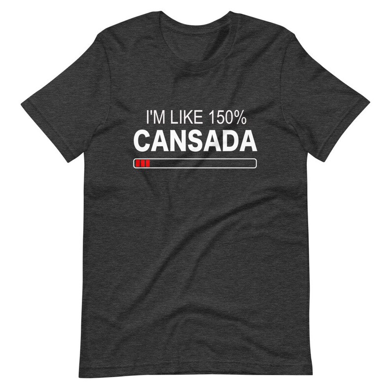 May include: A dark heather grey t-shirt with white text that reads "I'm like 150% Cansada" with a progress bar underneath. The progress bar is filled with red.