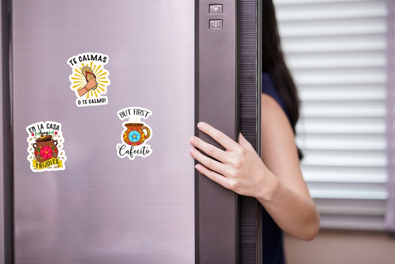 May include: Three refrigerator magnets with colorful designs and Spanish phrases. The magnets feature illustrations of a coffee cup, a pot of beans, and a flip-flop.