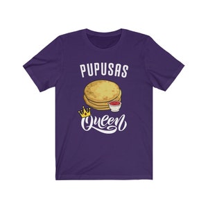 Puede incluir: Camiseta de manga corta de color morado con texto blanco que dice "Pupusas Queen" y una imagen de dibujos animados de pupusas con un acompa&ntilde;amiento de salsa.
