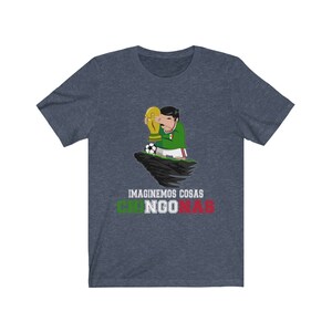 May include: Navy blue t-shirt featuring a cartoon figure in a green and white soccer uniform holding a gold trophy. A soccer ball sits nearby. The text "IMAGINEMOS COSAS CHINGONAS" is printed below the image in green and red.