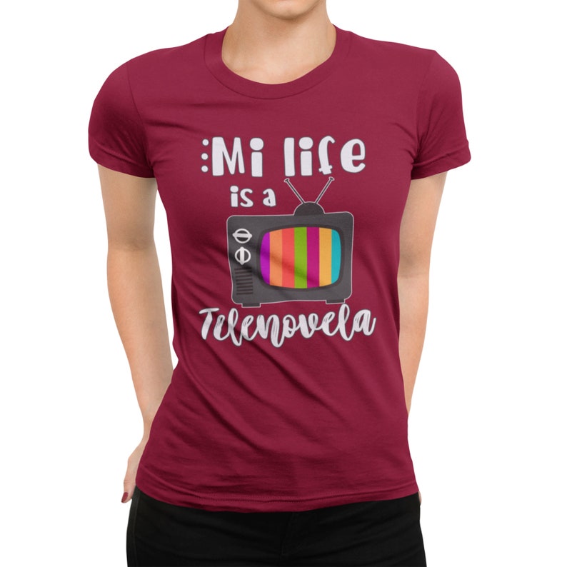 May include: A maroon t-shirt with the text "Mi life is a telenovela" and a cartoon image of a retro television set with a rainbow screen.