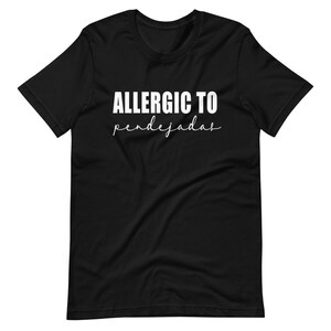 May include: Black t-shirt with white text that reads "ALLERGIC TO pendejadas".