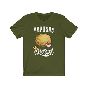 Puede incluir: Camiseta verde con el texto "Pupusas Queen" en blanco. Una imagen de dibujos animados de pupusas con un lado de salsa est&aacute; por encima del texto. Una corona dorada est&aacute; a la izquierda del texto.