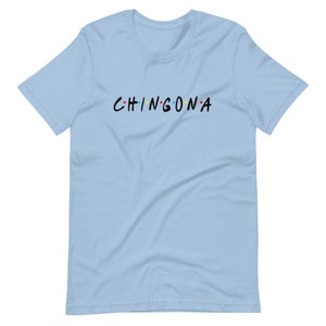 May include: Light blue t-shirt with the text "CHINGONA" in black with colorful dots between the letters.